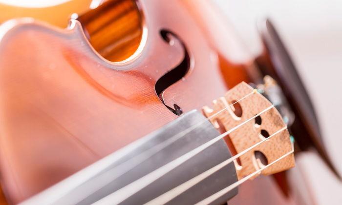 Nahaufnahme einer Violine mit sichtbarem Schallloch und Griffbrett, Saiten und Fensterlicht reflektieren.