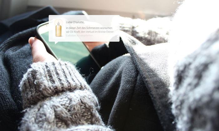 Person hält Smartphone mit einer Beileidsnachricht in der Hand.